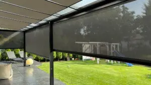 Rolety screen zip z napędem Somfy na pilota i z tabletu na tarasie zamontowane na słupach stalowych. Tkanina z kolekcji Serge 3% czarna. Prowadnice i skrzynka w kolorze czarnym.
